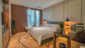 Une chambre d’hôtel moderne avec un grand lit, une table de chevet et un bureau avec une chaise.