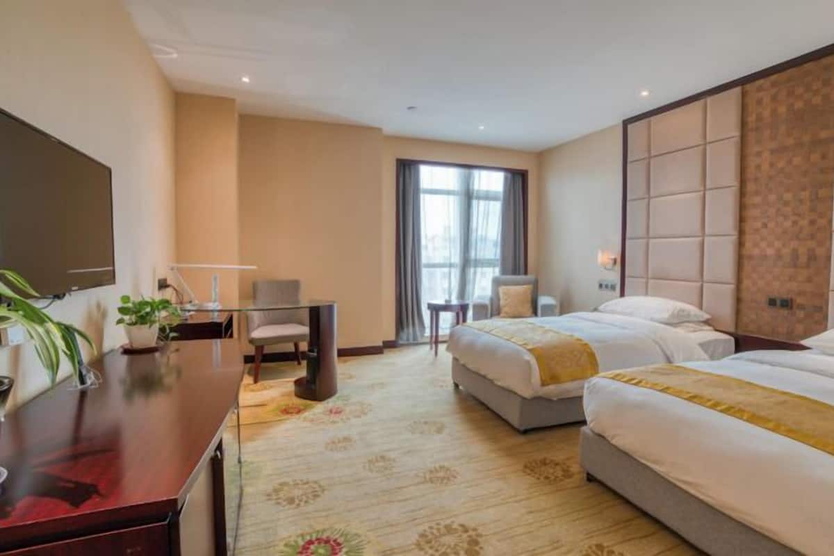Une chambre d’hôtel avec un lit, un bureau, une chaise, une télévision et une fenêtre.