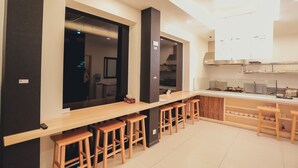 Una cocina moderna con una encimera larga, taburetes de madera y electrodomésticos integrados.