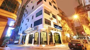 Un hotel de varios pisos con un diseño moderno, que destaca un cartel con el nombre "Momizi Hotels".