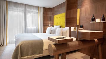 A modern hotel room with a large bed, wooden headboard, bedside table, and a mirror.