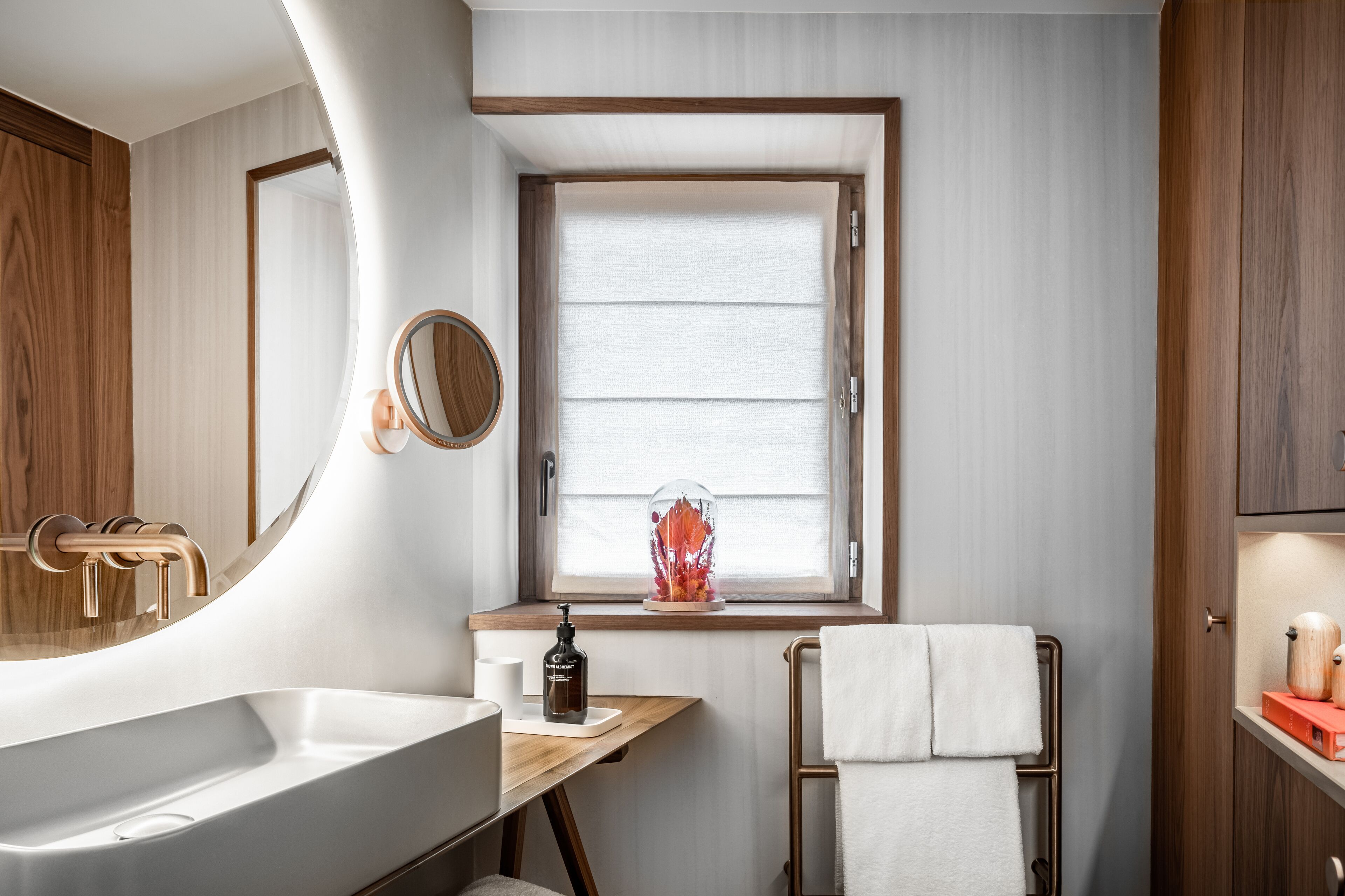Un baño moderno con un lavamanos grande, una ventana con persianas, un espejo y un perchero para toallas.