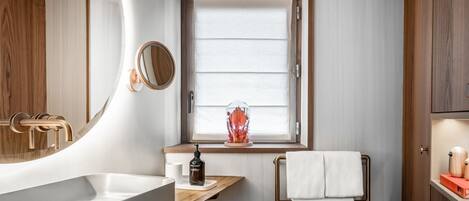 Un baño moderno con un lavamanos grande, una ventana con persianas, un espejo y un perchero para toallas.