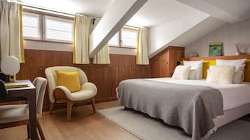 Un dormitorio con cama, una silla, un escritorio y una ventana con cortinas.