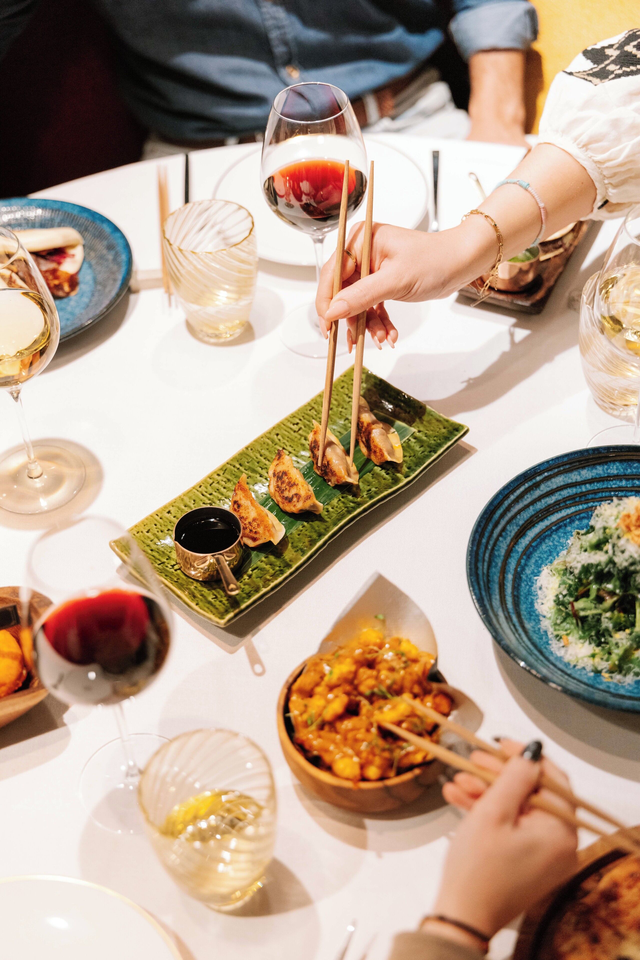 A dining table with various dishes, including dim sum, a bowl of soup, and a plate of rice.
