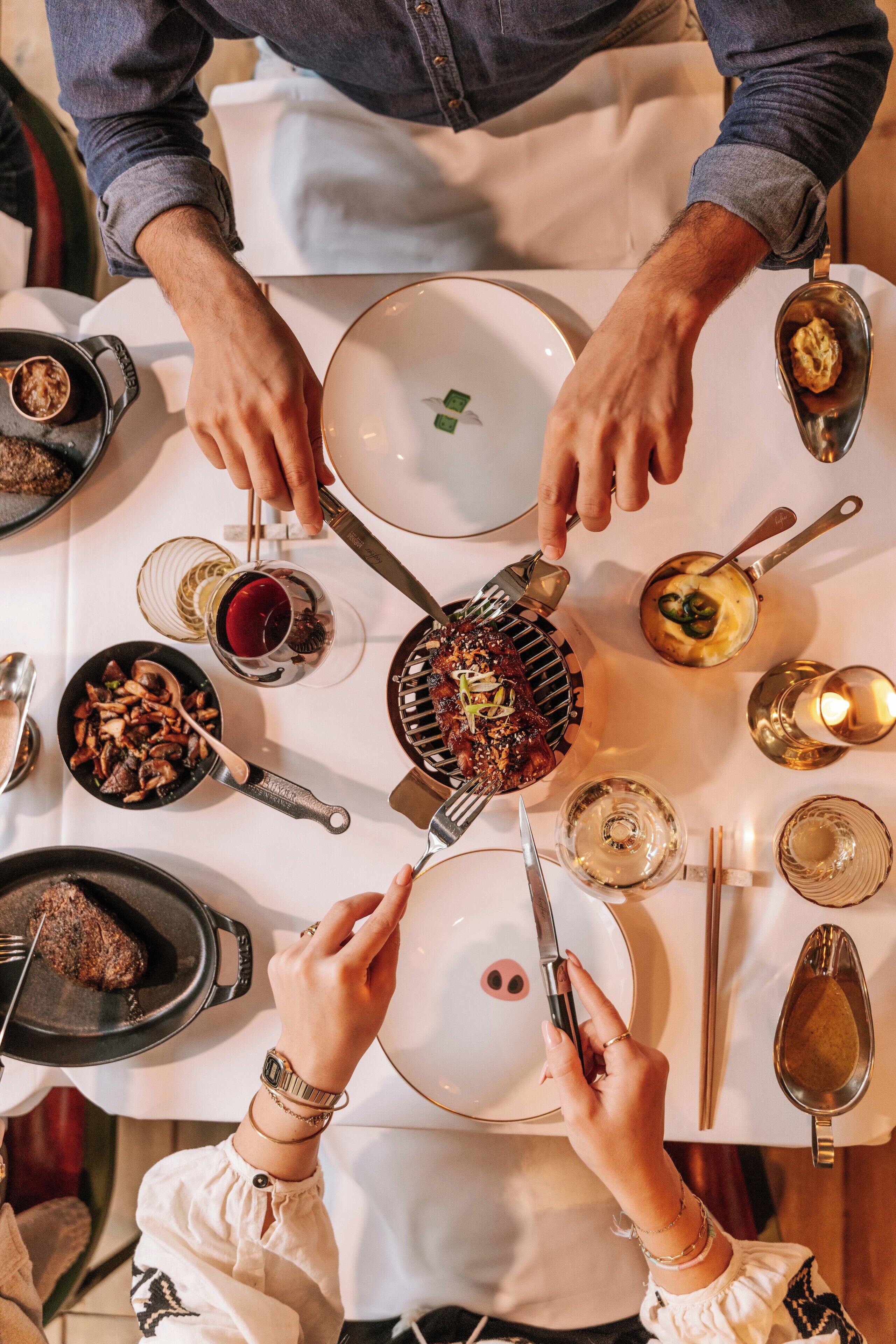 Una mesa de comedor con diversos platos y utensilios, incluyendo una plancha, platos y palillos.