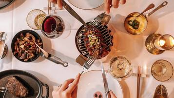 Una mesa de comedor con diversos platos y utensilios, incluyendo una plancha, platos y palillos.
