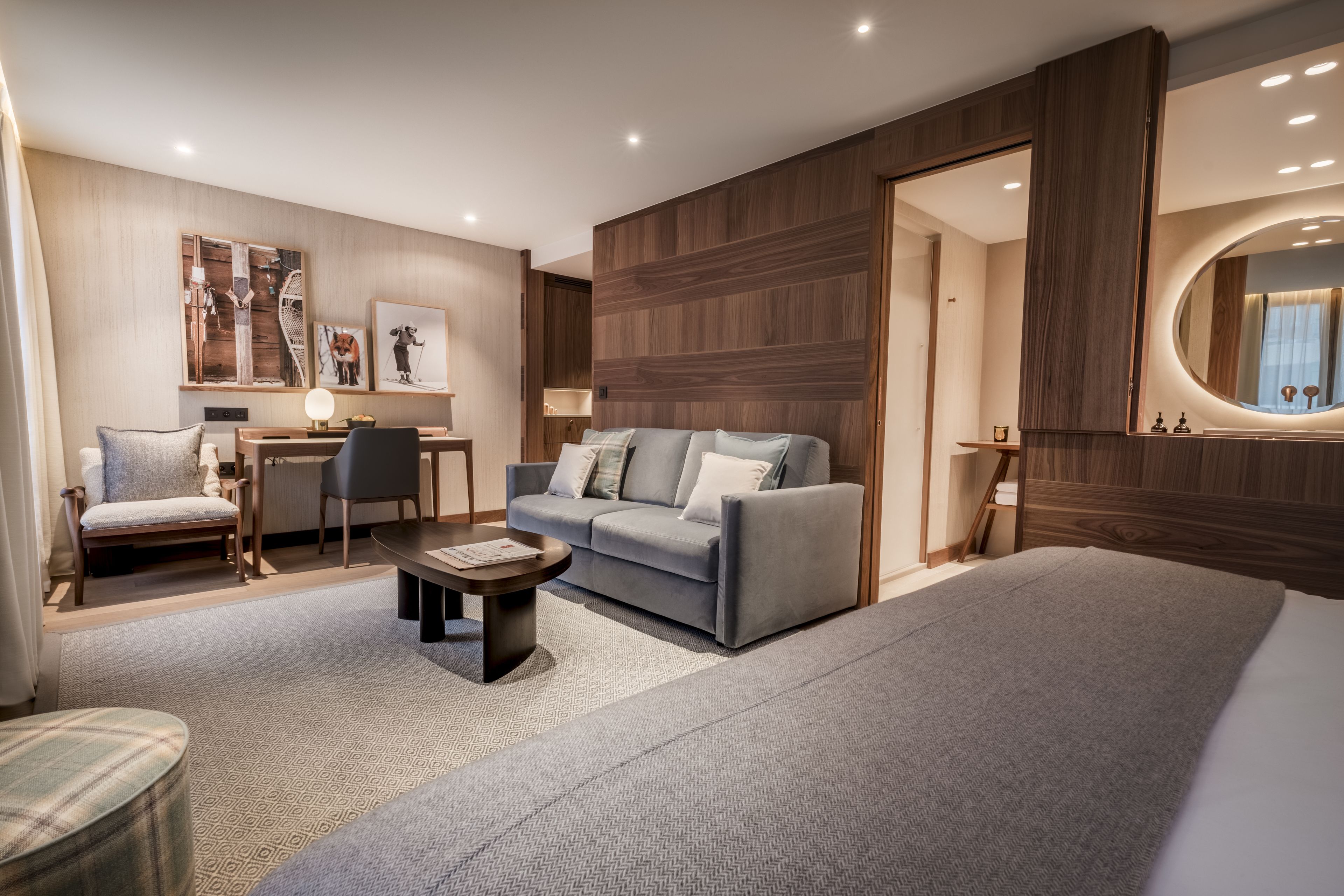 Una habitación de hotel moderna con sofá, sillón y una pequeña mesa.