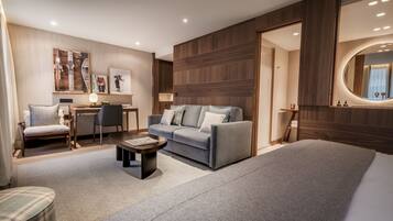 Una habitación de hotel moderna con sofá, sillón y una pequeña mesa.