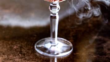 A cocktail glass with a smoky effect, placed on a textured surface.