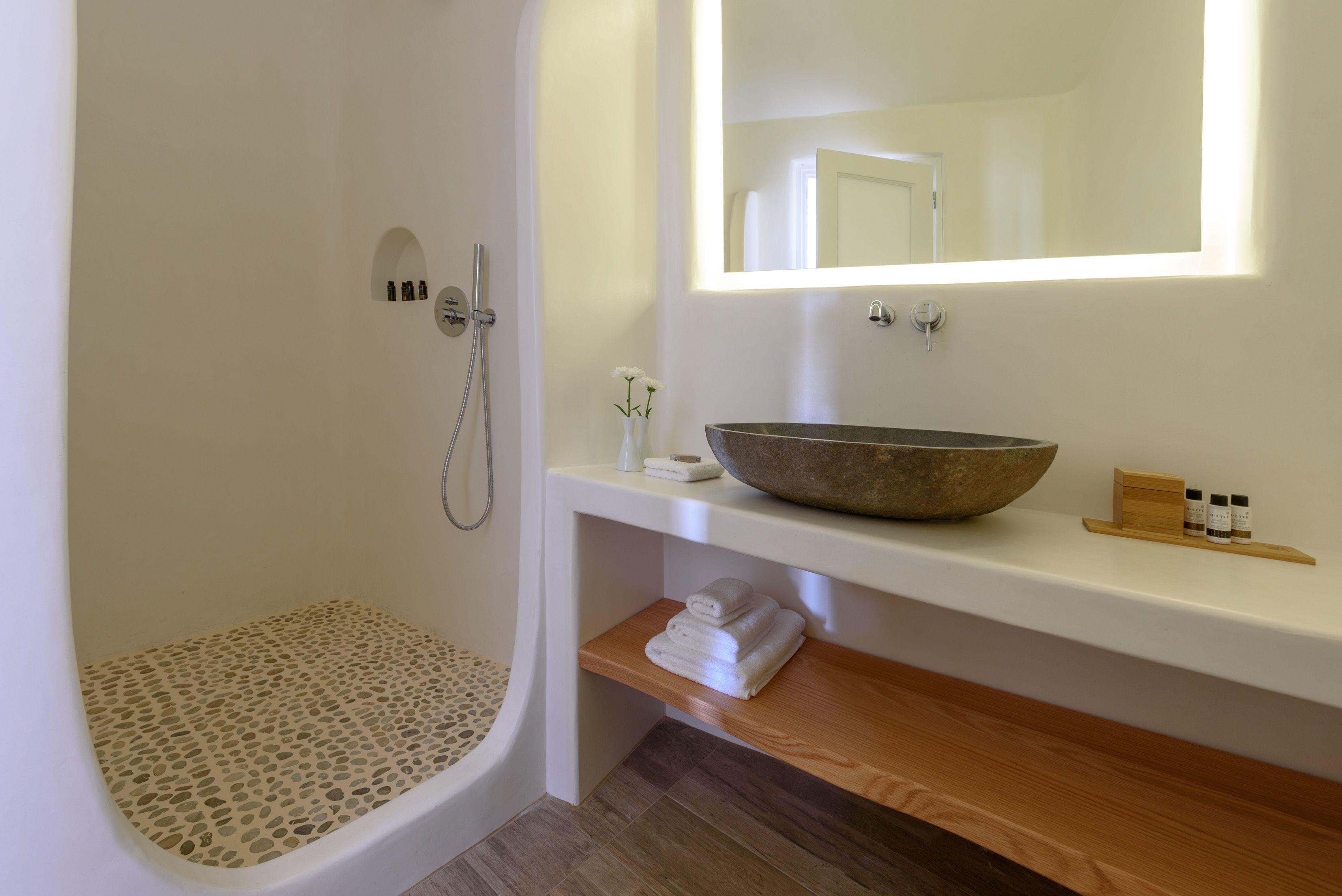 A modern bathroom with a freestanding bathtub, a large mirror, and a wooden vanity with a bowl sink.