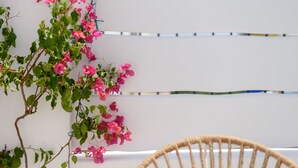 Un mur blanc orné de fleurs roses et une chaise en osier.