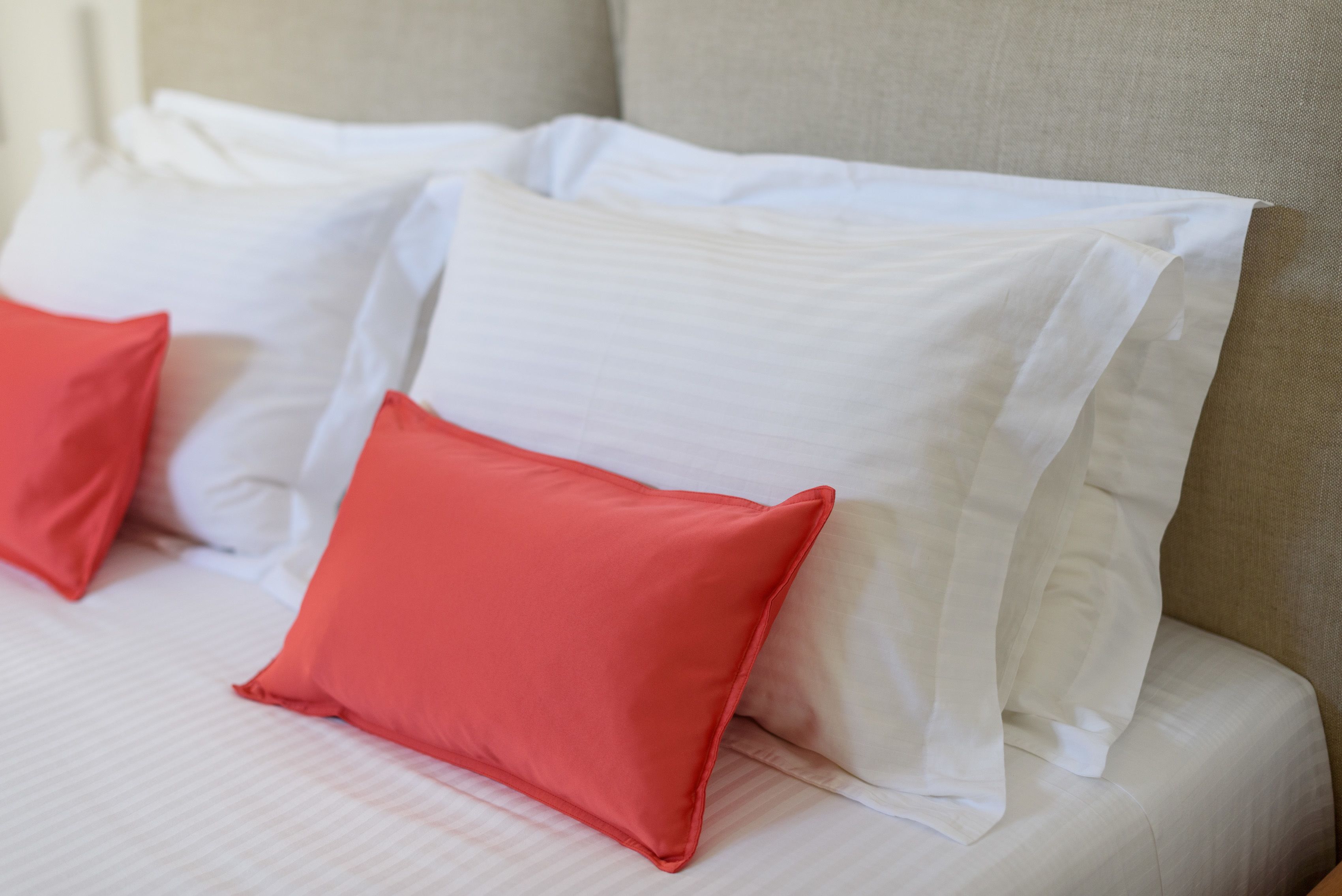 A bed with white and red pillows.