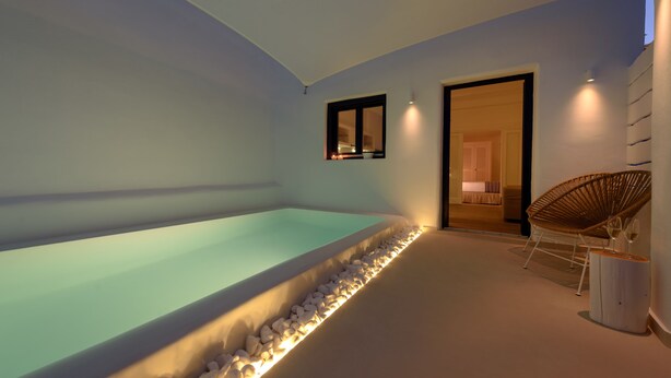 Un espace spa moderne avec une piscine chauffée, un fauteuil en osier et une petite table avec des verres.