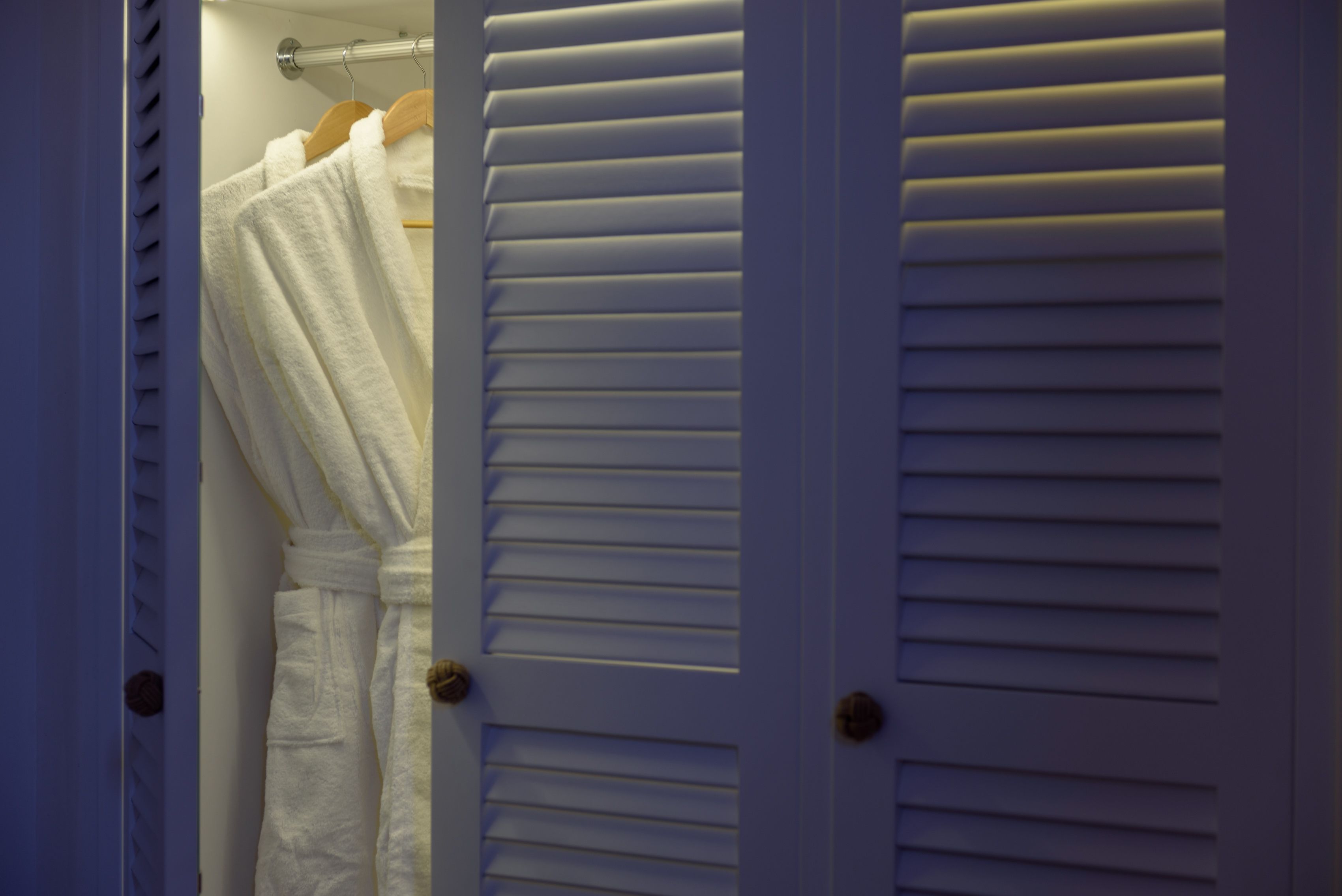 A white door with horizontal louvered panels and a wooden handle.