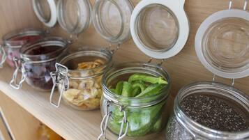 Una estantería con varios frascos de vidrio que contienen distintos alimentos.