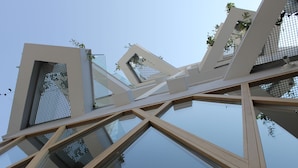 A modern building with geometric glass and metal structures, reflecting the sky and surrounding environment. - Qbic City Hotel (Larnaca)