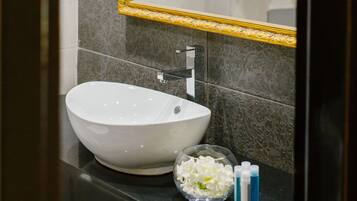 A bathroom with a white vessel sink, a gold-framed mirror, and a towel rack with neatly folded towels.