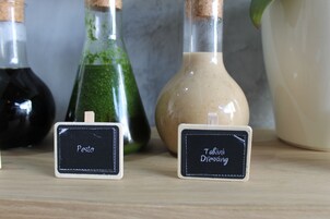 Three labeled bottles of dressing on a wooden surface.