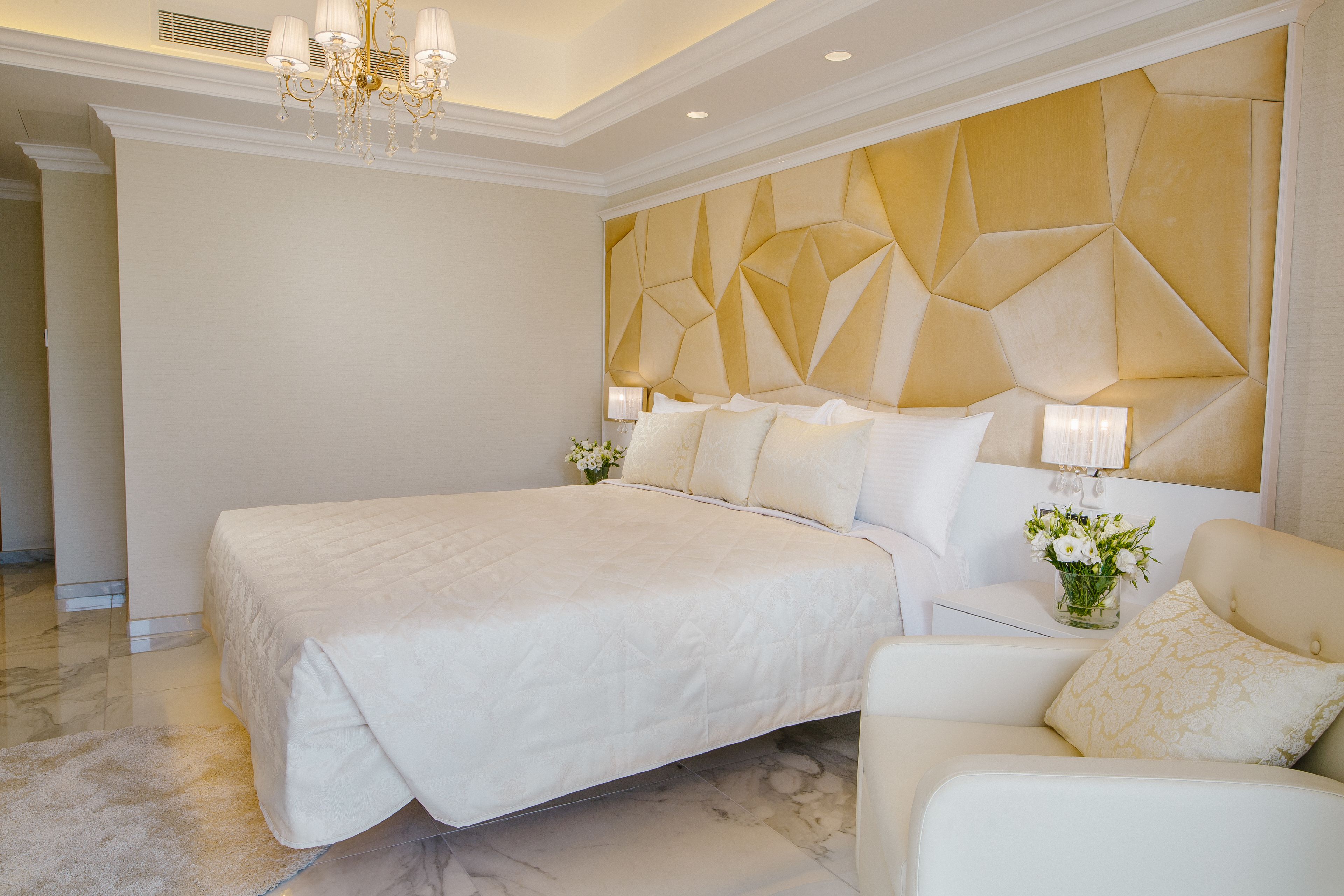 Un'ampia camera da letto con un grande letto, un comodino con una lampada e un pannello decorativo a parete.