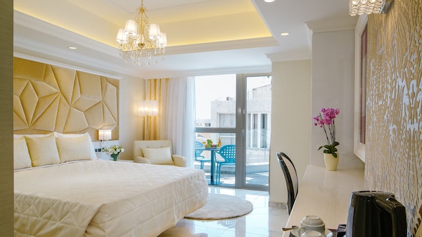 A hotel room with a large bed, a dining table with two cups and a coffee maker, and a balcony with a table and chairs. - Qbic City Hotel (Larnaca)