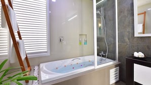 A modern bathroom with a freestanding bathtub, a glass shower enclosure, and a large mirror. - Velana Beach Hotel Maldives (Maafushi)
