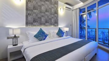 Una habitación de hotel moderna con una cama grande, dos lámparas de noche, un papel tapiz estampado y un balcón con vistas.
