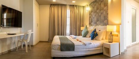 A modern hotel room with a bed, a desk, a TV, and a large window with curtains.