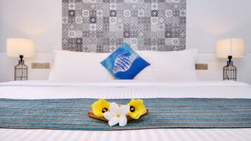 Una cama bien hecha con una colcha azul y blanca a rayas, un cojín decorativo y una mesita de noche con una lámpara.