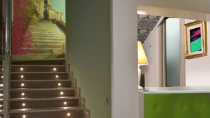 A staircase with illuminated steps, a green reception desk, and a wall-mounted TV. - Il Villino (Cagliari)
