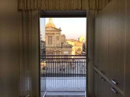 Un balcón abierto con vistas a un edificio histórico con cúpula y arquitectura clásica.