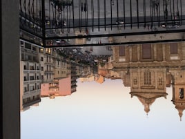Reflejo de un paisaje urbano en un ventanal, con edificios y una calle.