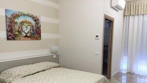 A bedroom with a bed, a painting on the wall, and a door leading to another room. - Affittacamere Duomo (Gela)