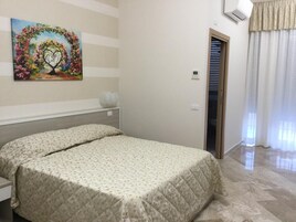 Un dormitorio con una cama, un cuadro en la pared y una puerta que da a otra habitación.