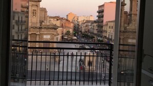 A balcony with a view of a cityscape, including buildings and a street with pedestrians. - Affittacamere Duomo (Gela)