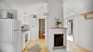 A modern kitchen with white cabinetry, a built-in oven, and a wooden floor. - Ljugarn Semesterby (Ljugarn)