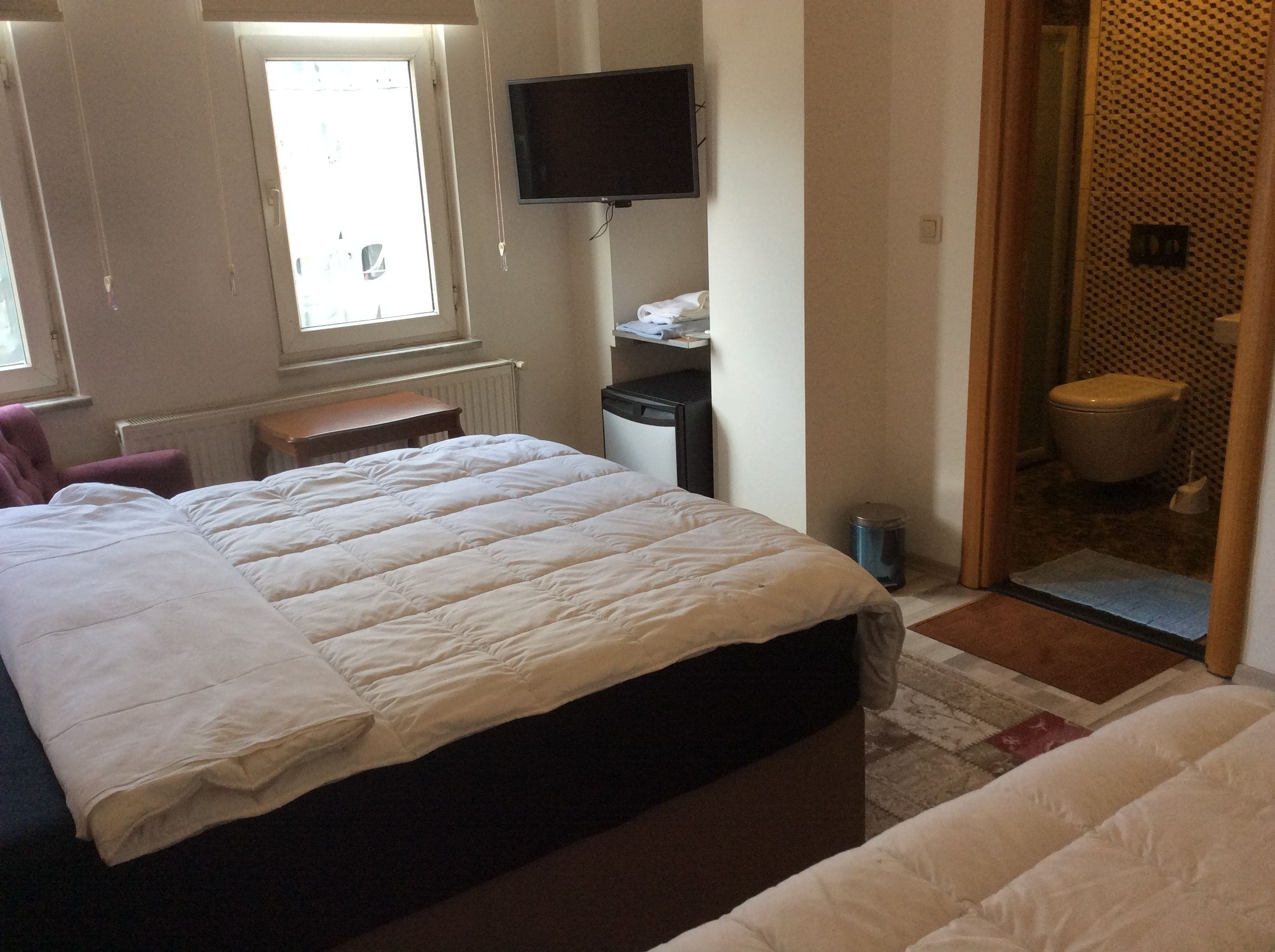 Een hotelkamer met een bed, een bureau, een televisie en een badkamer die door een open deur zichtbaar is.