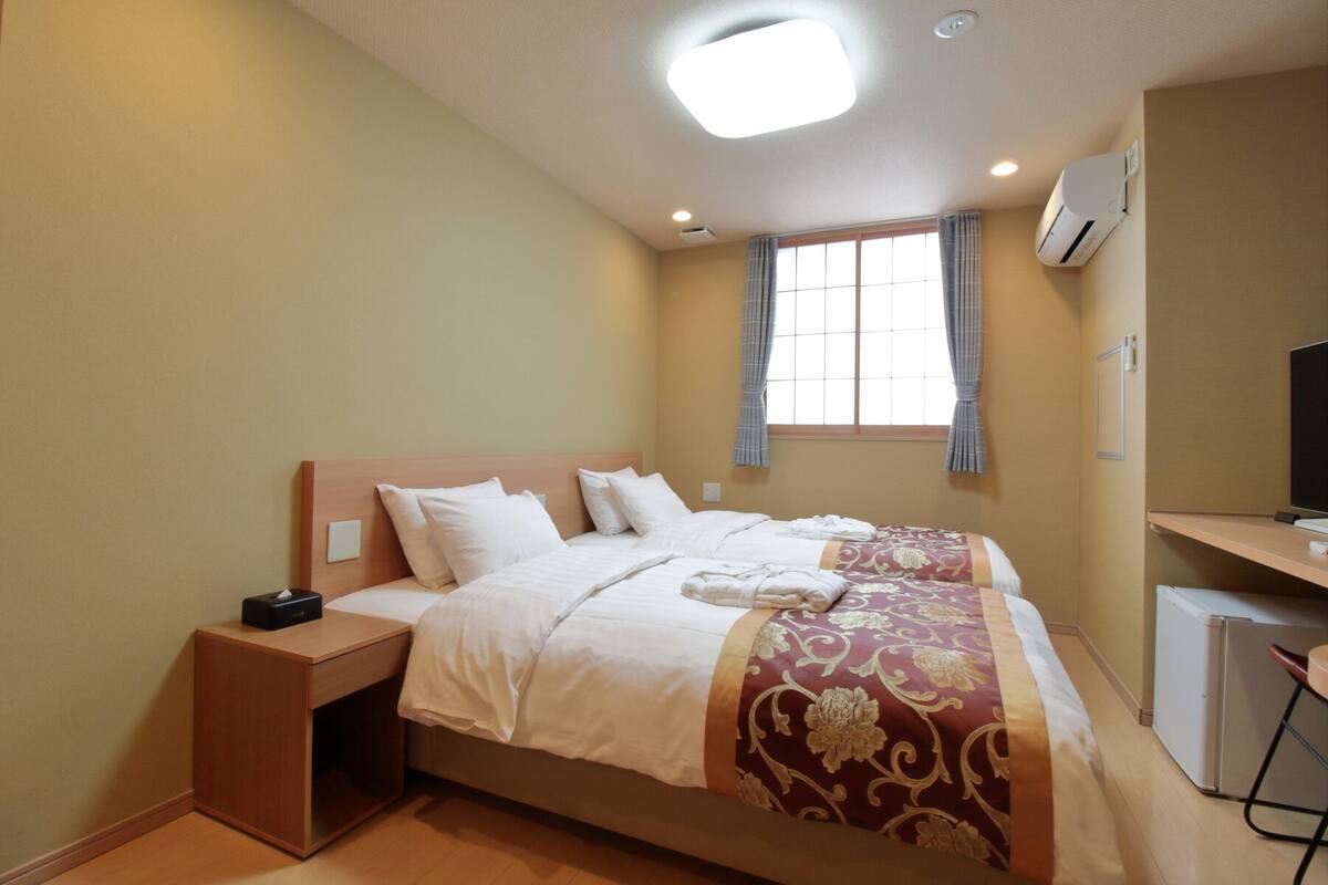 A hotel room with a bed, bedside table, and a desk with a chair.