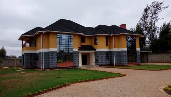 A two-story house with a tiled roof, large windows, and a paved driveway. - Karen Crescent Hotel (Nairobi)
