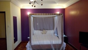 A room with a four-poster bed, a television on a stand, and a chandelier. - Karen Crescent Hotel (Nairobi)