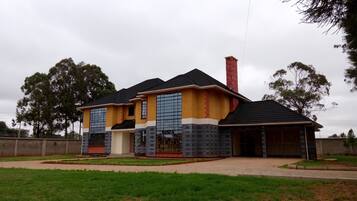 Una casa de dos pisos con techo de tejas, una chimenea y un garaje.