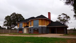 A two-story house with a tiled roof, a chimney, and a garage. - Karen Crescent Hotel (Nairobi)