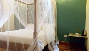 A bed with a white canopy, a small bedside table with a kettle, and a green wall. - Karen Crescent Hotel (Nairobi)