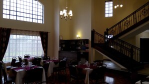 Un comedor con mesas dispuestas para comer, una zona de bar con botellas y una escalera que conduce a un nivel superior.