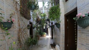 A narrow brick corridor with hanging planters and potted plants. - Yeşilköy Airport Butik Otel (Istanbul)