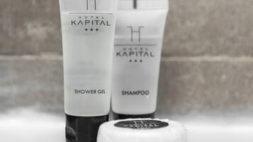 Dos productos del Hotel Kapital: un gel de ducha y un champú, con un tapón delante.