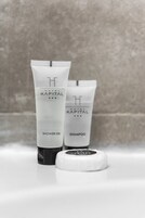 Dos productos del Hotel Kapital: un gel de ducha y un champú, con un tapón delante.
