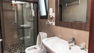 Un baño moderno con ducha envuelta en vidrio, un lavamanos blanco y un teléfono instalado en la pared.