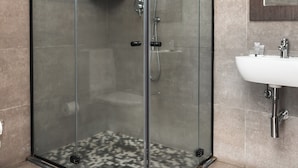 A modern bathroom with a glass-enclosed shower, a white sink, and a mirror above it. - Hotel Kapital (Maputo)
