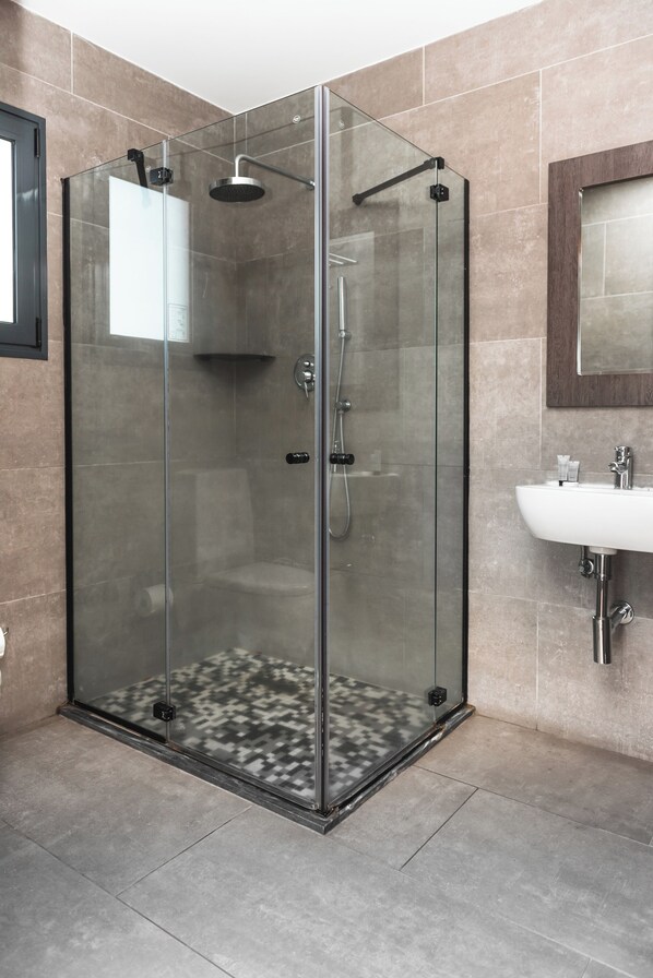 A modern bathroom with a glass-enclosed shower, a white sink, and a mirror above it. - Hotel Kapital (Maputo)